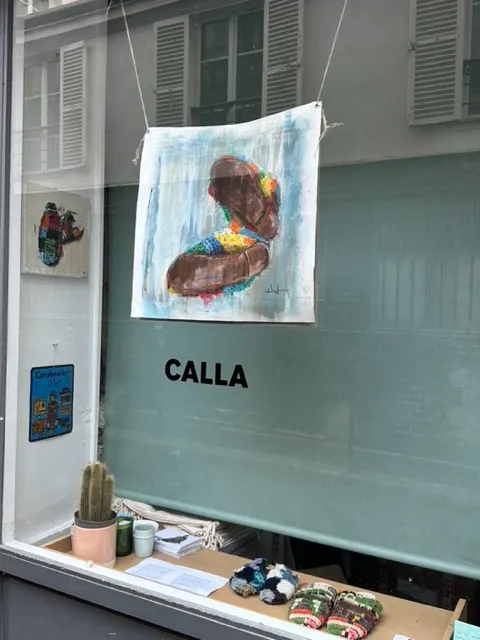 Painting in the Calla Paris window with the boutique signage