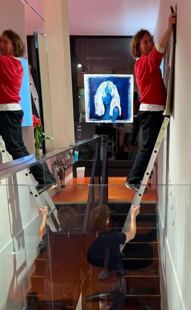 Installing the blue portrait above the staircase at Feel Soho