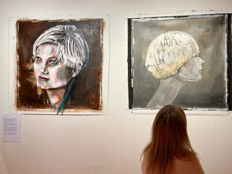 A visitor contemplating two portraits at Feel Soho